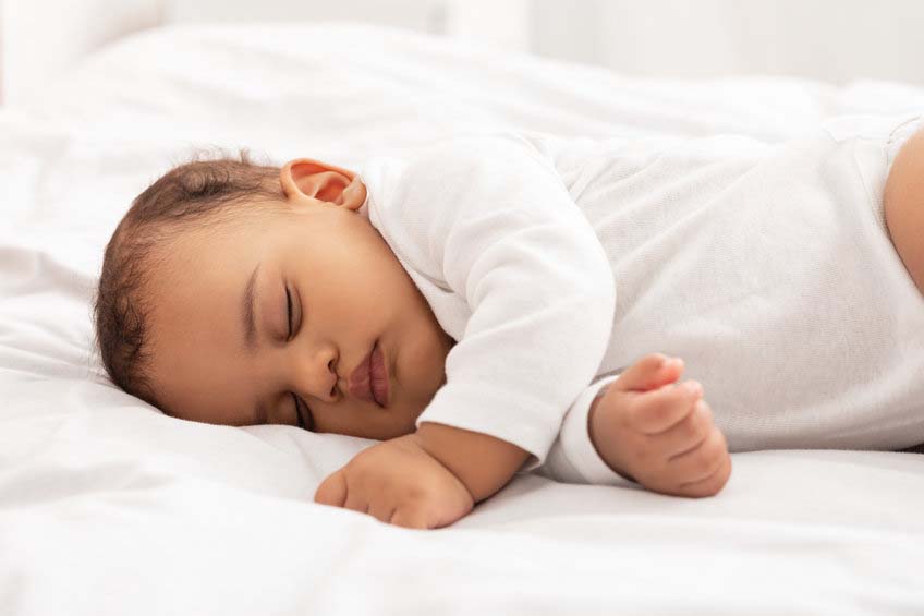 A sleeping baby resting peacefully on white bedding